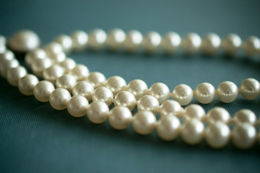 White pearl necklace laid on soft gray textile