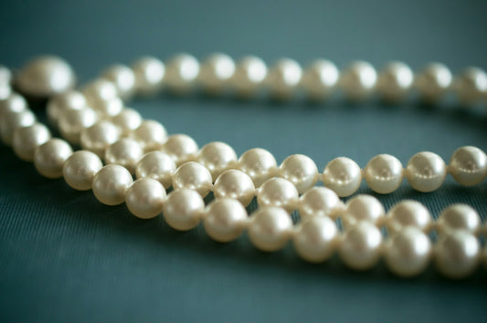 White pearl necklace laid on soft gray textile